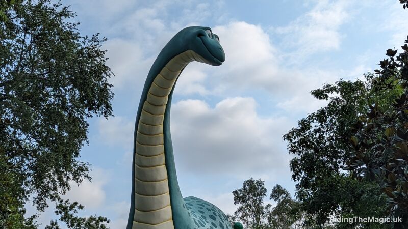 A happy dinosaur with a long neck looks out over the trees