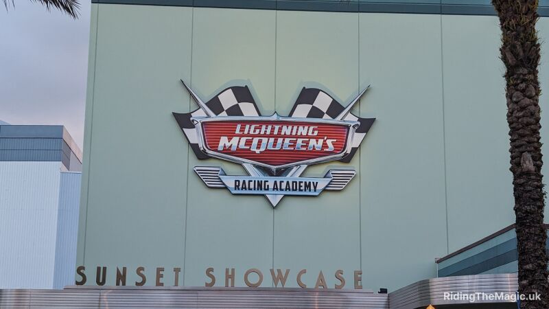 Signage for Lightning McQueens racing academy on the side of a building above the words Sunset Showcase