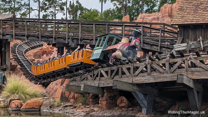 A rollercoaster comes down the track and heads into a corner with happy people putting hands in the air