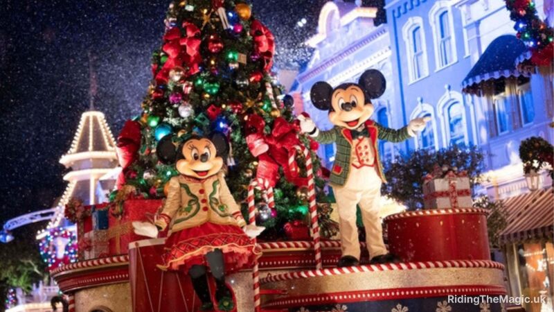 street backdrop, mickey and minnie mouse stand on gold and red float in red green and white outfits multi-coloured decorated Christmas tree behind them in float