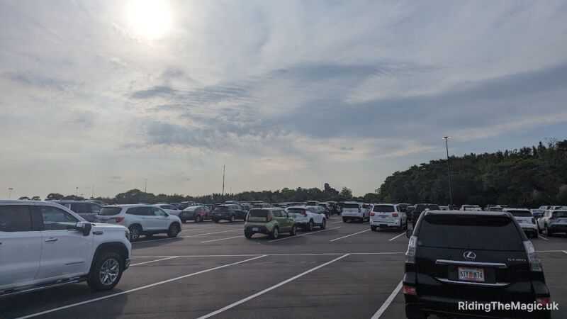 A parking lot filled with many cars, including SUVs, under a cloudy sky