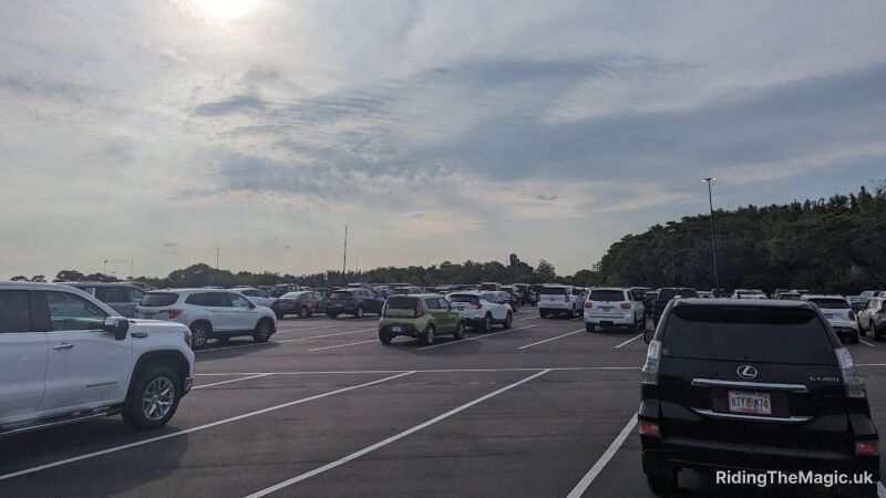 A parking lot filled with cars, SUVs, and trucks, under a cloudy sky