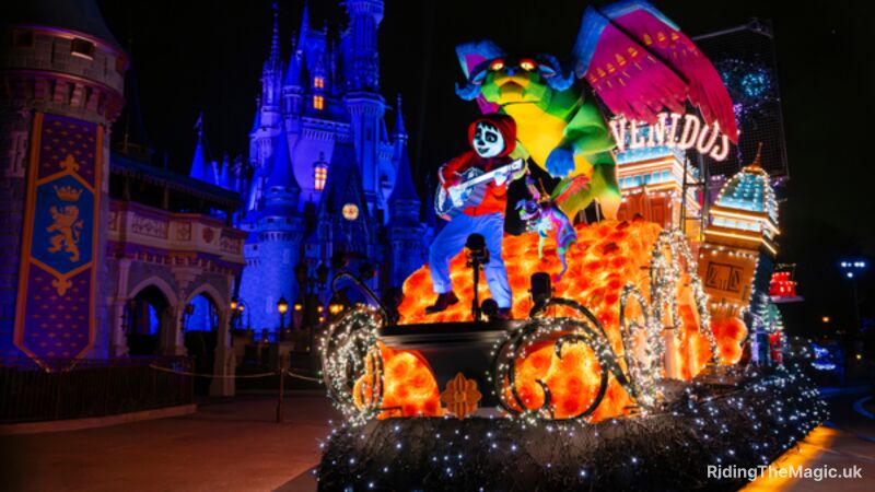 Nighttime parade float with a colorful dragon and a skeleton musician glowing in orange and blue lights in front of a lit castle.