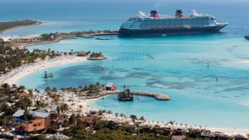 An aerial view of a beach with a cruise ship docked in the distance
