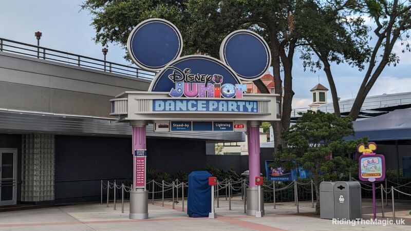 Mickey mouse ears over an arch with sign saying Disney Junior Dance Party, tree in background and metal rails