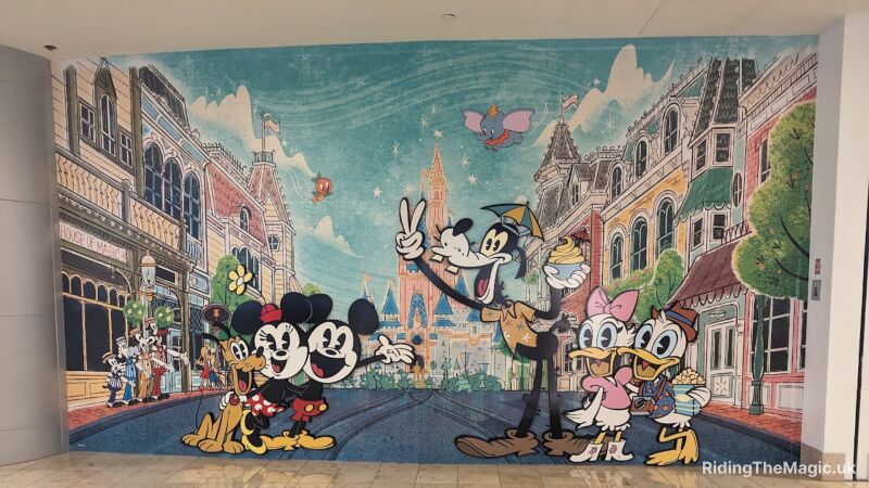 A mural of Mickey and Minnie Mouse and other Disney characters in front of buildings