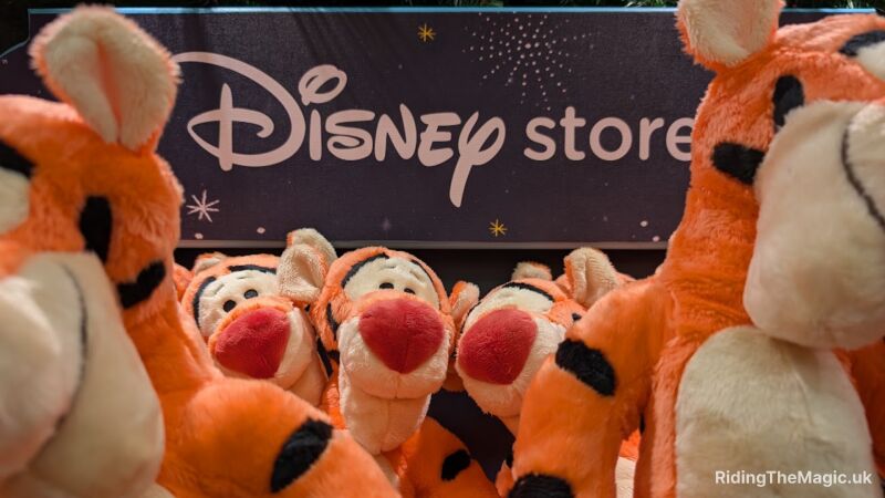 A group of orange and white Tigger plush toys in front of a Disney store sign