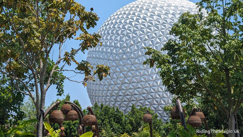 Epcot's Spaceship Earth with trees and hanging baskets in the foreground