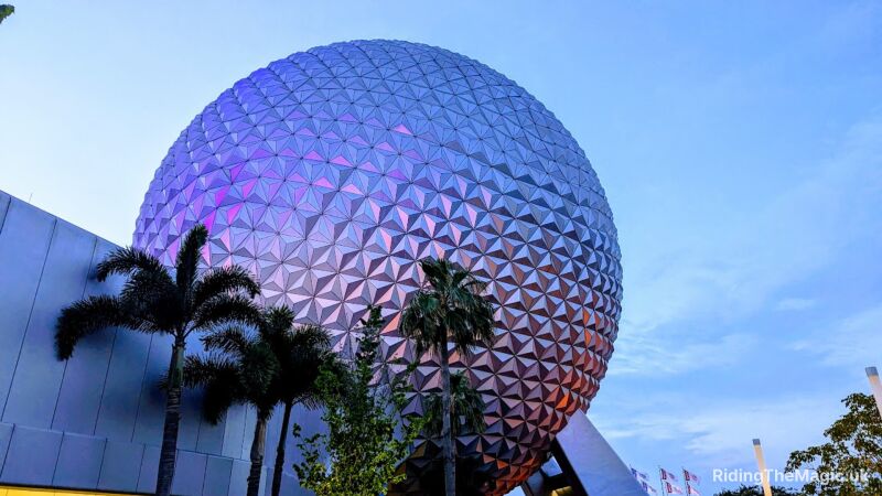 Epcot's Spaceship Earth is lit up at dusk with purple and pink lights