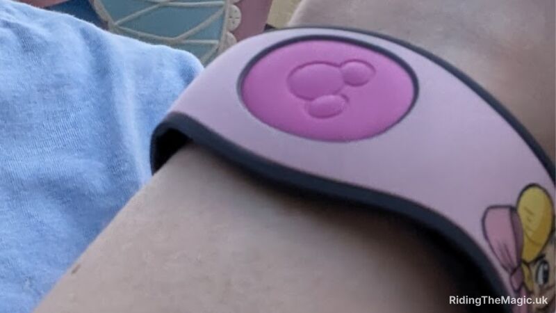 wrist with pink Magic Band on dark pink centre with Mickey Mouse face silhouette