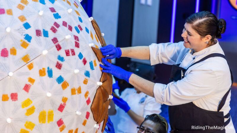 A woman in a white shirt and apron decorates a large spherical object