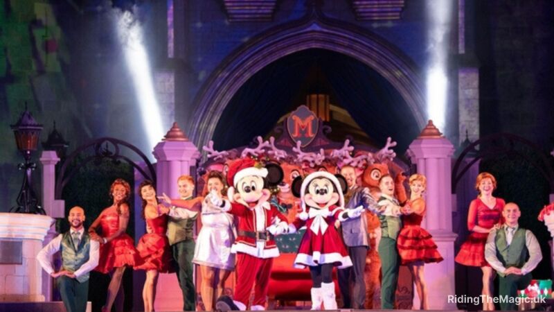 Mickey and Minnie in Christmas costumes on stage with other performers
