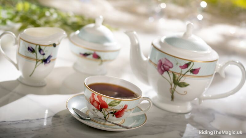 A tea set with a teapot, cup, saucer, and spoon on a marble table