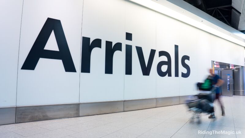 A person walking through an airport with the word "Arrivals" on the wall