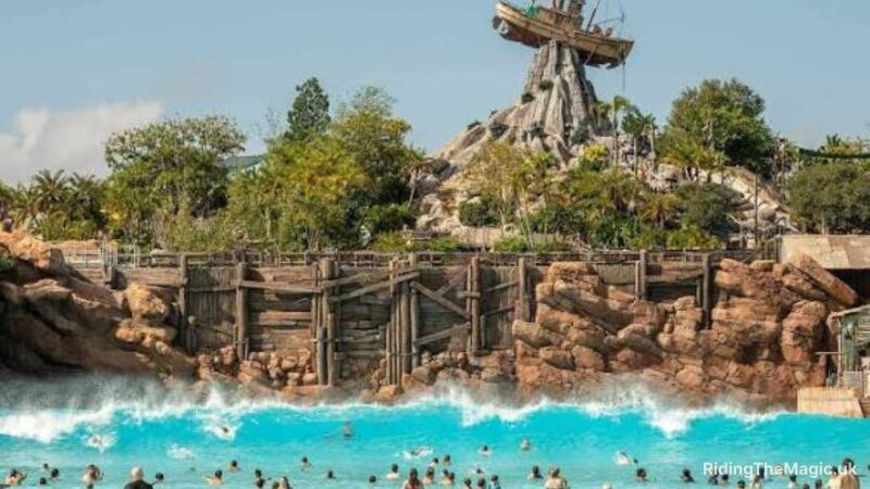 A wave pool with people swimming in it and a boat on top of a rock
