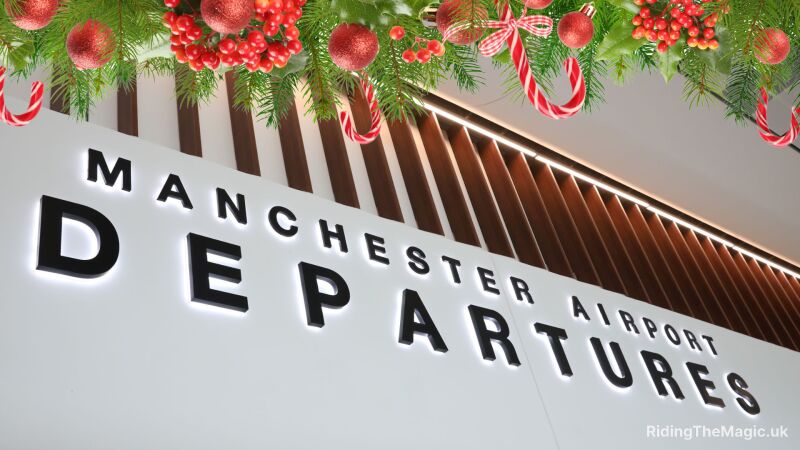 A Christmas tree with ornaments and candy canes hangs above the Manchester Airport Departures sign