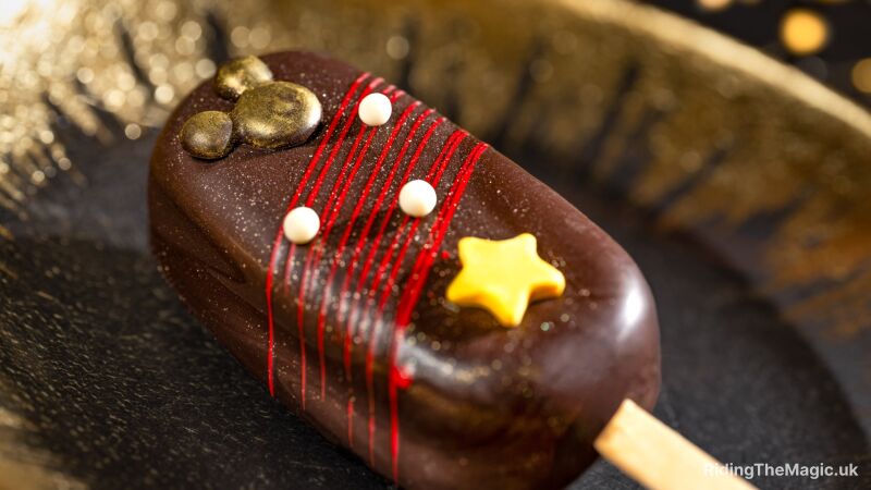 Chocolate popsicle with red stripes, white dots, and a yellow star on a gold background