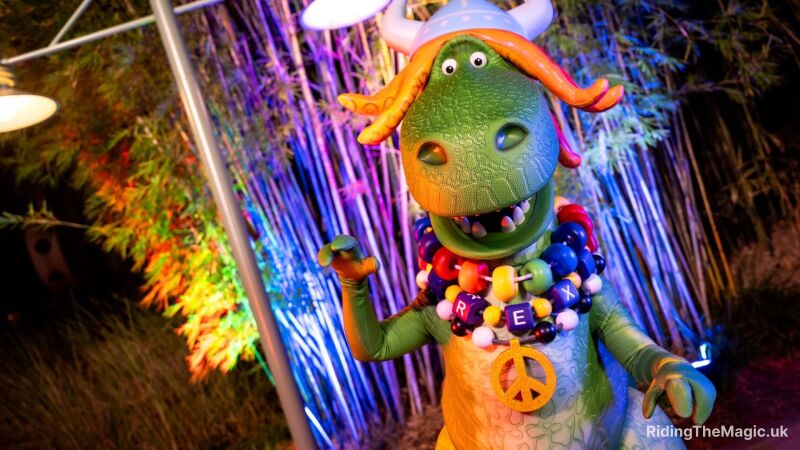 Partysaurus Rex from the Toy Story franchise at Jollywod Nights with a peace sign and beads saying "Rex"
