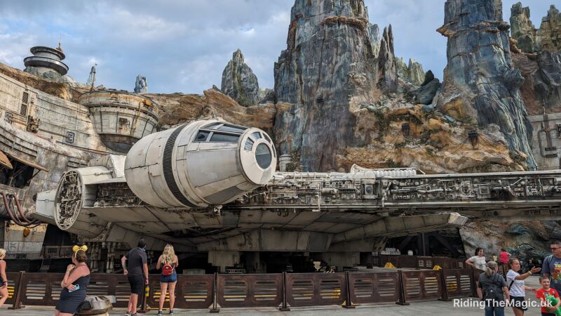 People standing around the Millennium Falcon in front of a rocky mountain Galaxy's Edge