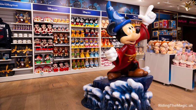 A Mickey Mouse statue in a store with shelves of toys and merchandise behind it