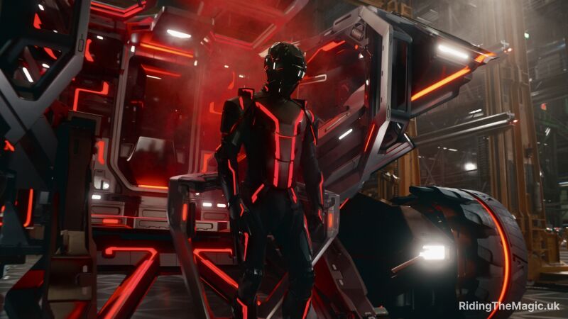 A person in a futuristic suit stands next to a red and black mechanical structure