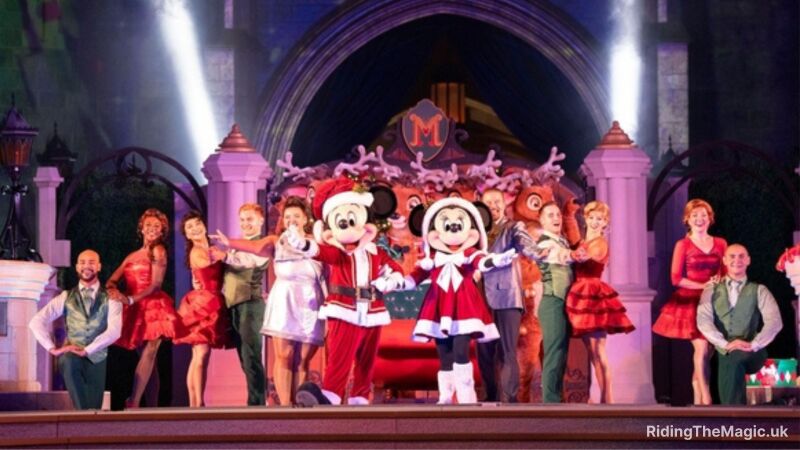 Mickey Mouse and Miinnie Mouse in Father Christmas style outfits arms open with dancers dressed in red, white and green coloured clothes on stage with arms open wide