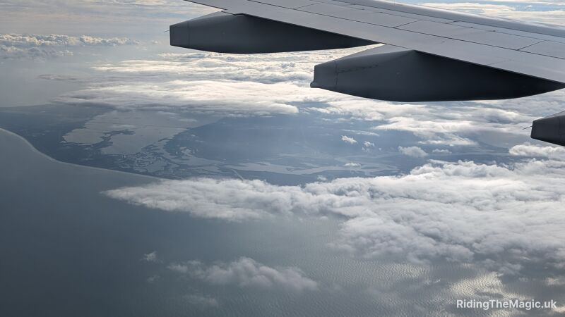 Aerial view of the ocean and clouds from an airplane wing