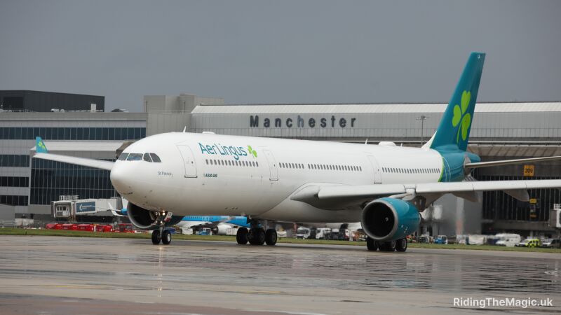 Aer Lingus plane on the runway at Manchester Airport with a cloudy sky in background