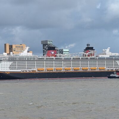 A large cruise ship sailing in the river with buildings on the sides