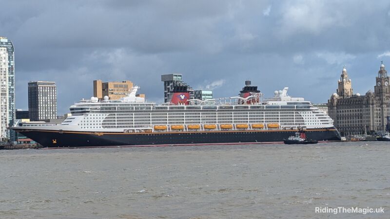 A large cruise ship sailing in the river with buildings on the sides